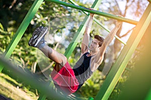 Man doing stomach workouts on horizontal bar outdoors