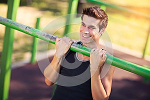 Man doing stomach workouts on horizontal bar outdoors