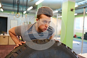 Man doing strongman tire flip training in gym photo