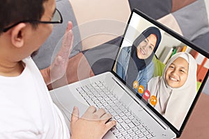 Man doing video call with his family at home, wife and daughter on laptop, remote virtual communication