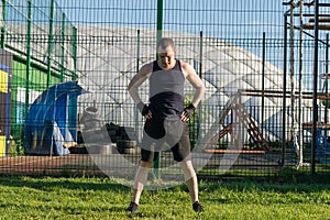 Man doing warm-up before strength training outdoors on green grass