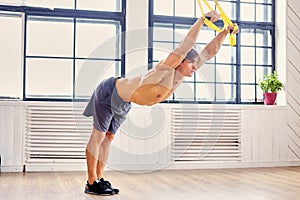 A man doing workouts with suspension trx straps.