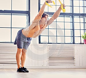A man doing workouts with suspension trx straps.