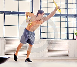 A man doing workouts with suspension trx straps.