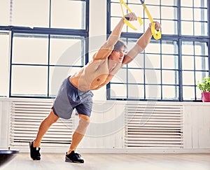 A man doing workouts with suspension trx straps.