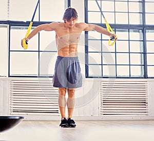 A man doing workouts with suspension trx straps.