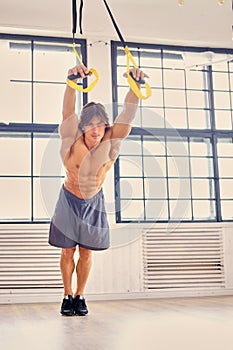 A man doing workouts with suspension trx straps.