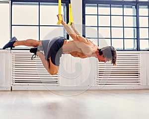 A man doing workouts with suspension trx straps.