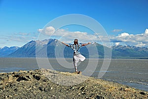 Man doing yoga at the coastline facing the mountains at Turnagain Arm