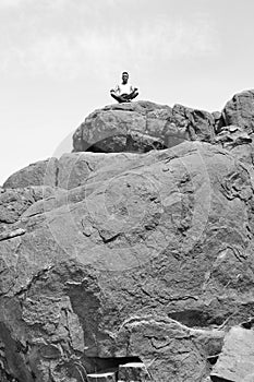 Man doing yoga concentration on a pile of rocks -B&W-