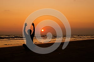 Man doing yoga exercise at sunset beach