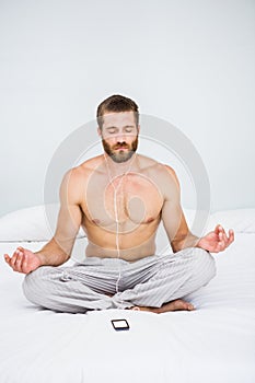 Man doing yoga while listening to music on bed