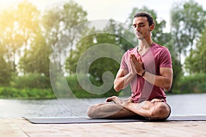 Man doing yoga meditation in nature near the river. Copy space
