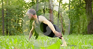 Man doing yoga in nice park.Sportsman shifting weight from one leg to another balancing on grass