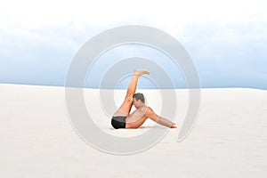 Man doing yoga on the sand