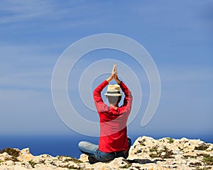 Man doing yoga in summer mountains