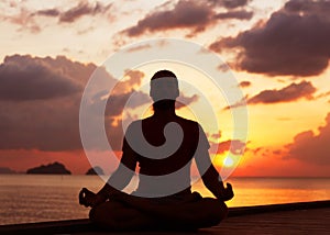 Man doing yoga at sunset