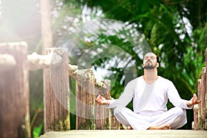 Man doing yoga in tropic jungle bridge