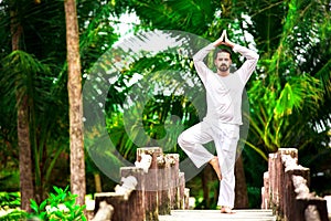 Man doing yoga in tropic jungle bridge