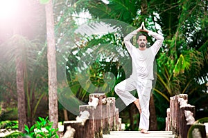 Man doing yoga in tropic jungle bridge