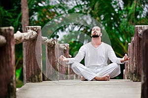 Man doing yoga in tropic jungle bridge