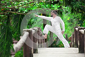 Man doing yoga in tropic jungle bridge