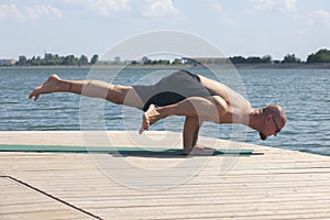 Man doing yoga on a wooden floor in the nature