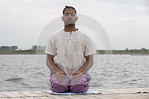 Man doing yoga on a wooden floor in the nature