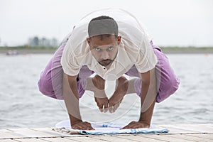 Man doing yoga on a wooden floor in the nature