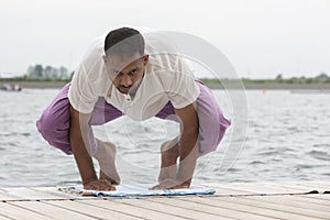 Man doing yoga on a wooden floor in the nature