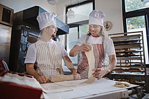 Man with down syndrom helping prepair bread in bakery with his colleague. Concept of integration people with disability