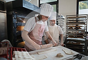 Man with down syndrom helping prepair bread in bakery with his colleague. Concept of integration people with disability