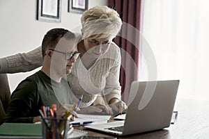 Man with down syndrome larning with mom at home photo