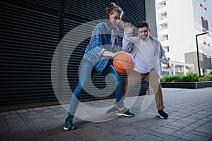 Man with down syndrome playing basketball outdoor with his friend. Concept of friendship and integration people with