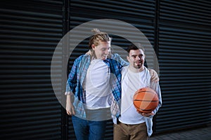 Man with down syndrome playing basketball outdoor with his friend. Concept of friendship and integration people with