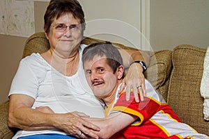 Man With Downs Syndrome Hugs His Older Sister On A Couch