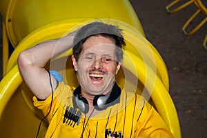 Man With Downs Syndrome Laughs and Plays on a Playground Slide