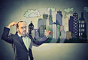 Man drawing city skyline on gray wall background