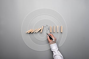 Man drawing the outline of a businessman stopping the domino eff