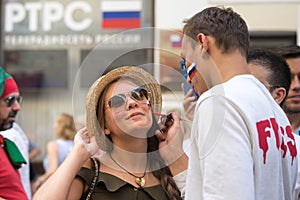 Man drawing russian flag on the cheek of the young woman sport fan