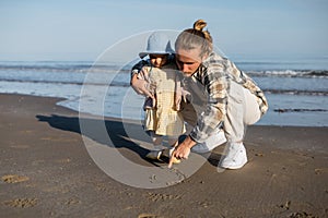 Man drawing on sand near toddler