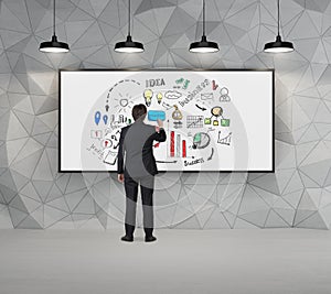 Man drawing sketch on whiteboard in concrete room