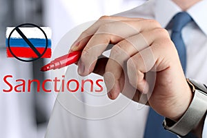 Man drawing a word sanctions by a red pen . photo