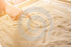 A man draws on the sand symbol of the smiling sun