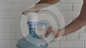 Man draws water into a glass from a hand pump