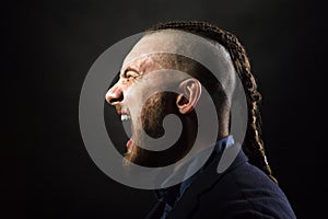 Man with dreadlocks screams in a rage, looks like a viking, Iroquois haircut