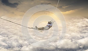 Man Dreaming in Rocking Net Above Sky