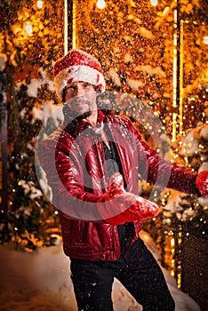 Man dressed as Santa Claus poses on a street decorated with garlands. New Year and Christmas concept