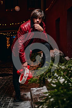 Man dressed as Santa Claus poses on a street decorated with garlands. New Year and Christmas concept