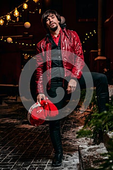 Man dressed as Santa Claus poses on a street decorated with garlands. New Year and Christmas concept